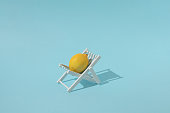 istock Fresh lemon on a beach chair with blue background. Colorful creative summer food concept. 1399353956