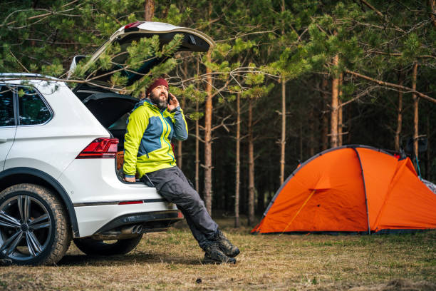 istock A man talking on the mobile phone while sitting in the open trunk of an SUV. 1399354881