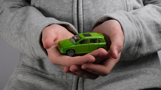 Green toy car in the palms of the hands.