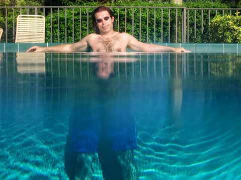 Partially underwater shot of man standing in outdoor swimming pool with clear clean water in Florida