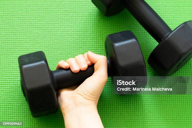 Females Hand Holding A Dumbbell On Green Workout Mat Background Stock Photo - Download Image Now