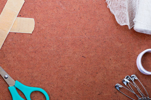 First aid kit items on a textured background: bandage plaster, medical gauze, scissors, safety pins, and non-woven tape. Copy space for text. Top view, flat lay. Emergency help on traveling concept.