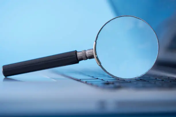 Photo of magnifying glass resting on the laptop keyboard