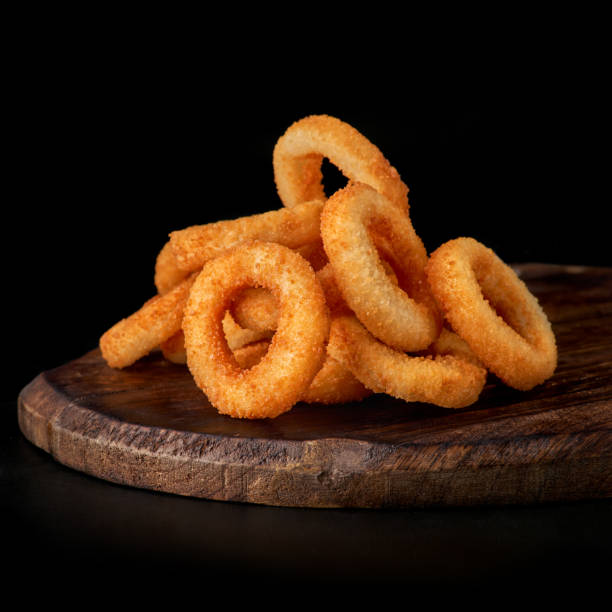 selective focus. fried onion rings in breadcrumbs fried in oil. restaurant serving. on a dark background. for menus and ads selective focus. fried onion rings in breadcrumbs fried in oil. restaurant serving. on a dark background. for menus and ads. Copy space, menu fried onion rings stock pictures, royalty-free photos & images