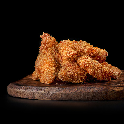 Coloque patas de pollo fritas, nuggets de pollo en una bandeja de madera, aislados en negro. photo