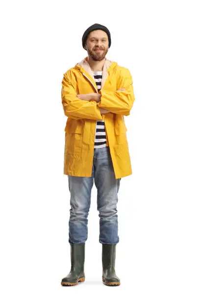 Full length portrait of a fisherman in a yellow raincoat and rubber boots isolated on white background