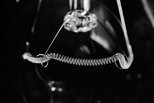 Tungsten filament in incandescent lamp, macro close-up. Black background.