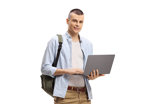 Happy young man with a backpack smiling and making eye contact while standing on the college hallway