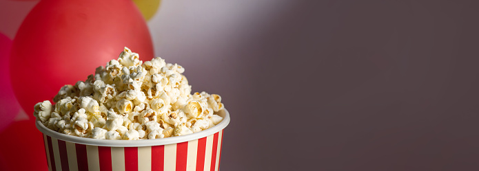 Kids cinema deals. Black little girl wearing 3D glasses and eating popcorn with dazed face expression, standing over yellow background, panorama