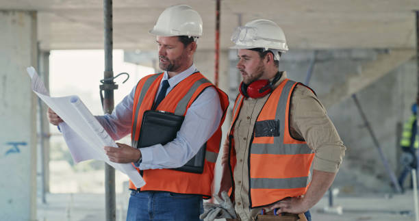 istock Builders reading a blueprint and talking at a construction site. Two men working as a team on an architecture project. Engineers and colleagues discussing plans 1399364881