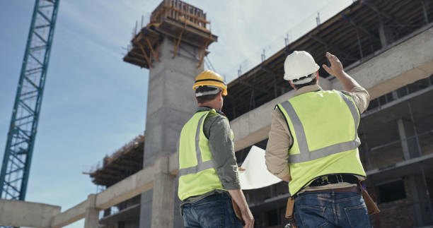 istock Builders reading a blueprint and talking at a construction site. Two men working as a team on an architecture project. Engineers and colleagues discussing plans 1399364903