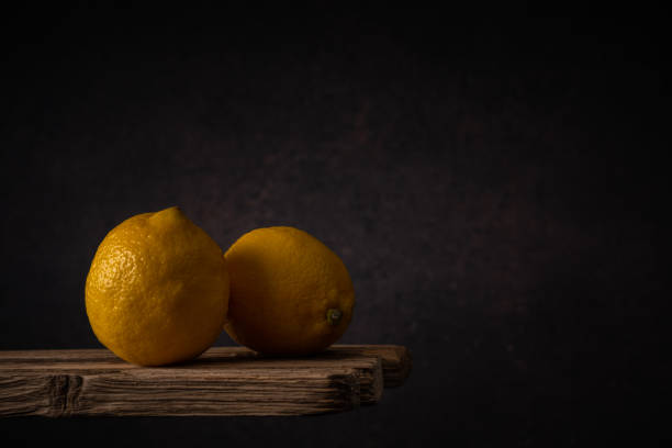istock two ripe lemons lie side by side on old boards against a dark backdrop. moody artistic still life with copy space 1399365049