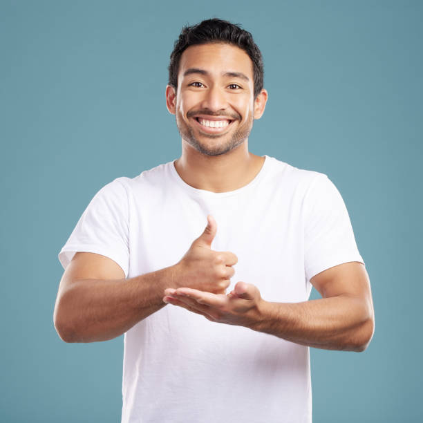 istock Handsome young mixed race man giving thumbs up while standing in studio isolated against a blue background. Hispanic male showing support or appreciation. Backing or endorsing a product or company 1399365918