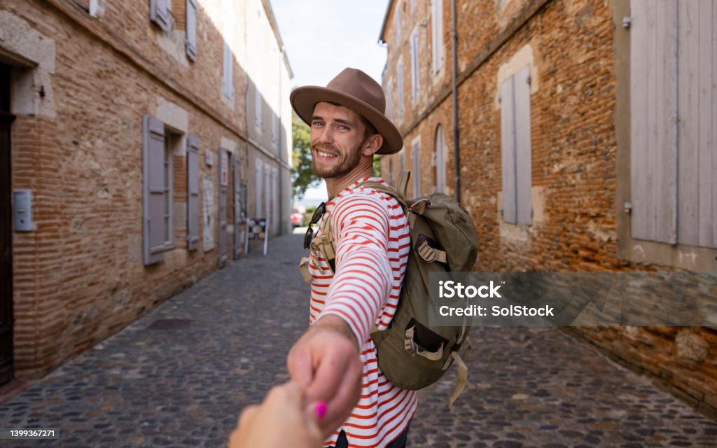 Hold My Hand A point of view of a male traveler in a fedora holding her partner's hand as they travel in the streets of Auvillar in Toulouse in the South of France. Toulouse Stock Photo