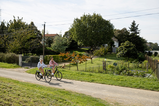 A wide angle side view of two young woman enjoying as bike rise while they holiday in Toulouse in the South Of France.