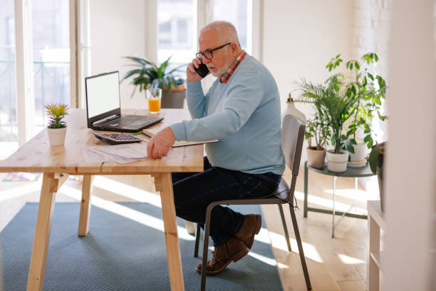 istock Pensive aged man using laptop paying bills online at home. Senior businessman work on computer. 1399367565