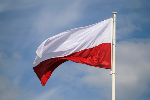 flag of poland against blue sky and white clouds