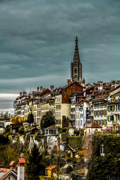 view of moody sky above traditional architecture and bern minster cathedral in bern, switzerland - medieval autumn cathedral vertical imagens e fotografias de stock