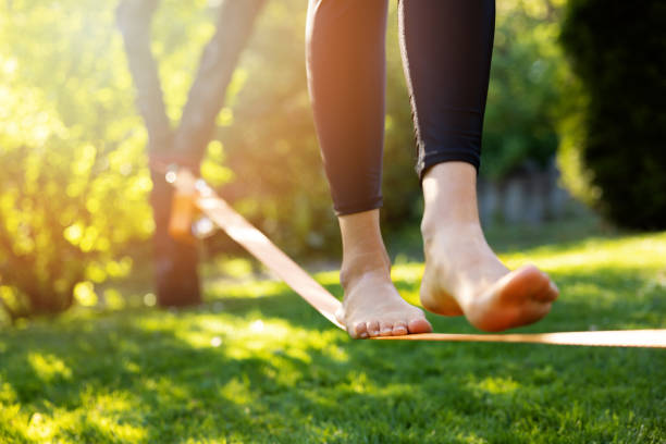 istock woman walking on a slackline in a park at sunset. core balance training 1399371027