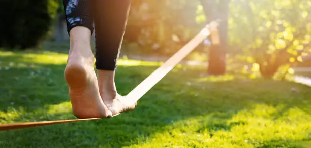 Photo of person walking on a slackline barefoot. strength and balance exercises