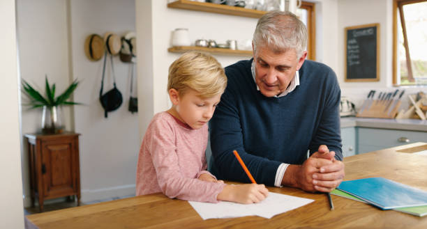 istock Boy learning with grandfather at home. A senior man and his grandson doing homework, drawing and getting an education while sitting at a table 1399371991