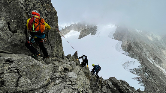 Hiking group mountain climbing in European Alps together. Using a rope