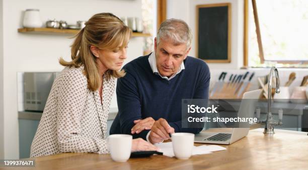 A Senior Couple Planning Their Finance And Paying Bills While Using A Laptop At Home A Mature Man And Woman Going Through Paperwork And Working Online With A Computer Stock Photo - Download Image Now