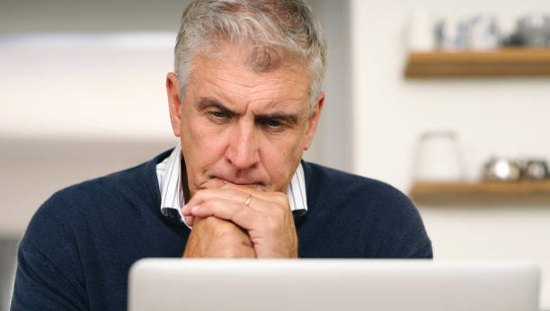 istock A senior man planning his finance, paying bills and thinking, looking unhappy while using laptop at home. A mature man working online with a computer and feeling confused, stressed and unsure 1399376473
