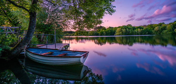 Rowing boat tied up on lake under a glorious duskily purple sky