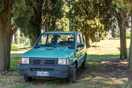Old car parked under some trees in Italy