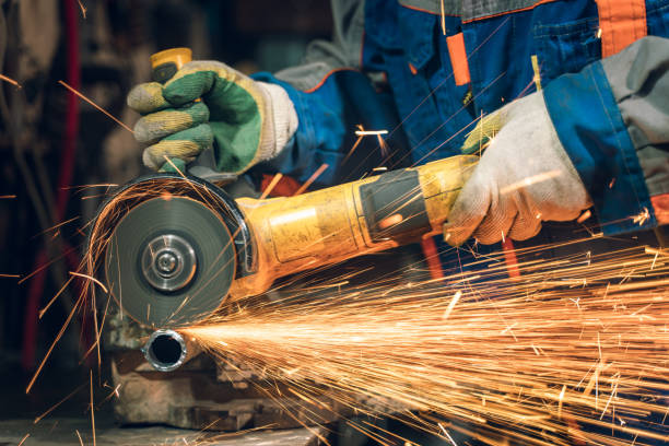 istock Locksmith in special clothes and goggles works in production. Metal processing with angle grinder. Sparks in metalworking 1399384009