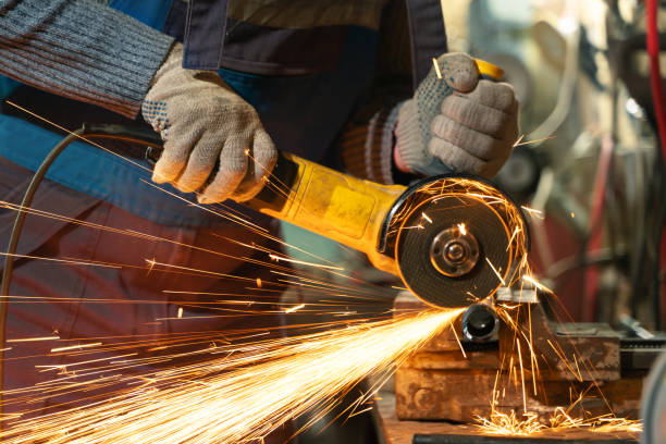 istock Locksmith in special clothes and goggles works in production. Metal processing with angle grinder. Sparks in metalworking 1399384753