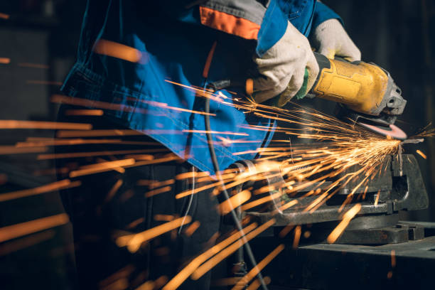 istock Locksmith in special clothes and goggles works in production. Metal processing with angle grinder. Sparks in metalworking 1399385432