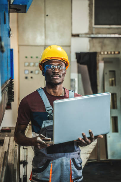 Technician using laptop while working in a factory stock photo