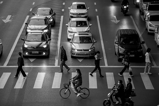 People walking on the zebra crossing in front of vehicles at dusk time in Chengdu, China. High ISO, noise is advised.