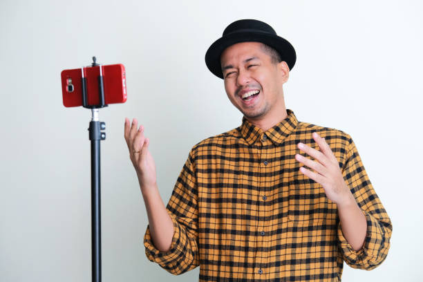 Adult Asian man laughing happy during video call with his friend Adult Asian man laughing happy during video call with his friend keluarga stock pictures, royalty-free photos & images