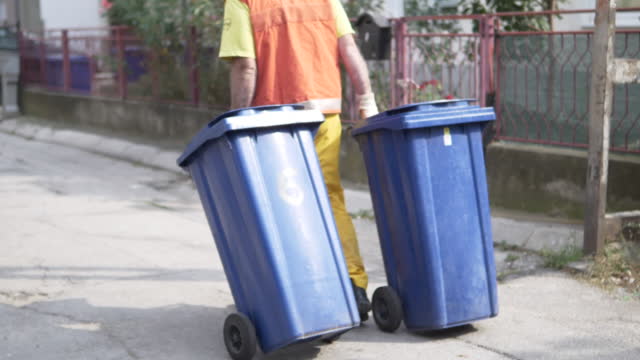 Sanitation worker dragging garbage bins