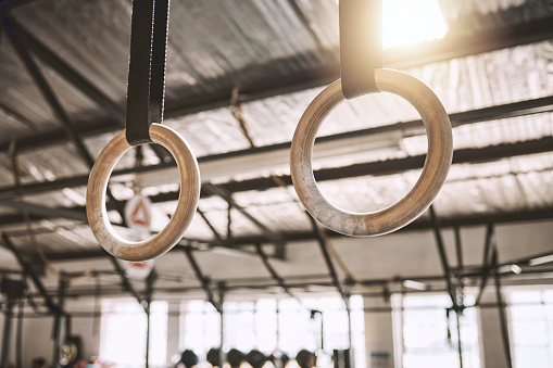 Gymnastic rings hanging in a gym. Empty gym with workout equipment. Acrobat rings hanging in a gym. Empty gym with exercise objects. Gym interior training equipment. Fitness can be flexible