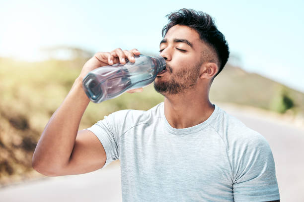 istock Fit young mixed race man drinking water from a bottle while exercising outdoors. Handsome hispanic male taking a sip of water during a break from his workout outside. Cardio and endurance training 1399392530