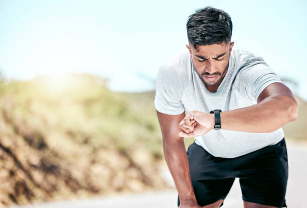 istock Athletic young mixed race man looking at his watch while exercising outdoors. Handsome hispanic resting while checking the time on his smartwatch during a workout. Tracking progress while working out 1399392547
