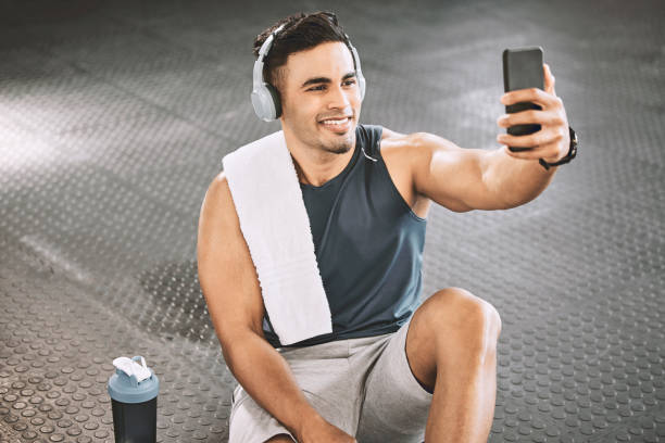 istock Healthy bodybuilder taking selfies in the gym. Fit trainer taking a break from exercise to take a photo on his cellphone. Handsome athlete taking selfies on his smartphone at the gym. 1399393908