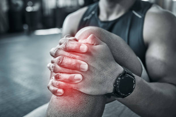 Sprained knee joints hurt. Athlete holding their hurt knee in the joint. Bodybuilder sitting in the gym with a knee cramp. Physical pressure will result in muscle problems. Care for your body muscles dolor en las articulaciones de la rodilla torcidas. atleta sosteniendo su rodilla lastimada en la articulación. culturista sentado en el gimnasio con un calambre en la rodilla. la presión física resultará en problemas musculares. cuida los músculos de