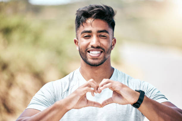 istock Portrait happy fit young mixed race man making a heart shape with his hands while exercising outdoors. Handsome hispanic man showing that he loves to work out, stay healthy and run outside in nature 1399393971
