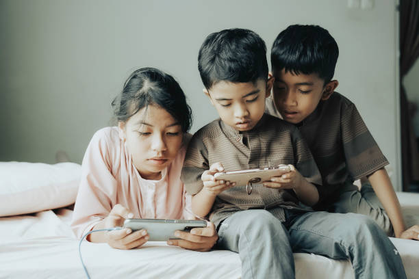 tre bambini che giocano con i moderni dispositivi mobili - tablet e smartphone - smart phone china mobile phone asia foto e immagini stock