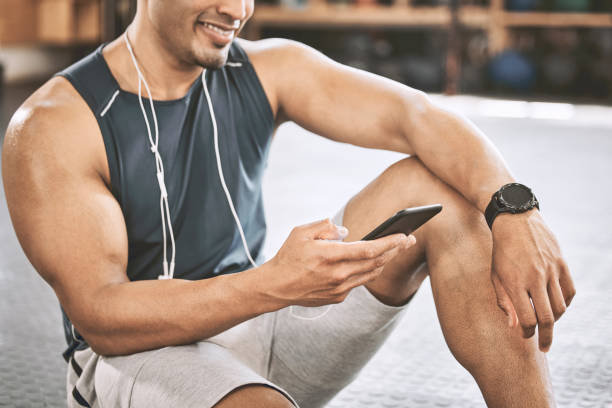 istock Happy trainer reading a text on a cellphone. Fit athlete taking a break to use their cellphone. Bodybuilder sending a message on their smartphone. Keeping connected in the gym. Communication is key 1399394444