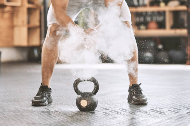 istock Dusting before power lifting. Bodybuilder getting ready to lift a heavy kettlebell. Athlete ready to lift weights. Sporty, muscular trainer using powder before a weight lifting routine. 1399394447