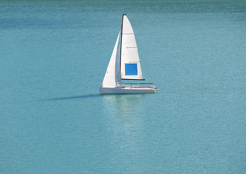 Regatta sailing boat at blue water background