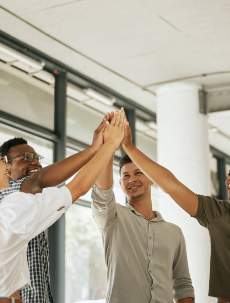 istock Smiling creative business team standing in office and giving high five during team building. Diverse business people celebrating their success together at startup 1399395709