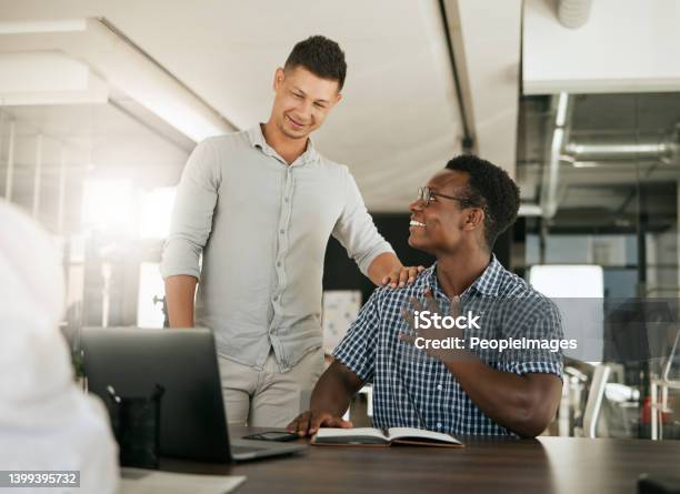 Two Diverse Businessmen Talking At A Desk Discussing New Project On Laptop Mentor Complimenting Colleague On A Job Well Done And Being A Fast Learner In Modern Office Stock Photo - Download Image Now