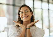 istock Cheerful business woman with glasses posing with her hands under her face showing her smile in an office. Playful hispanic female entrepreneur looking happy and excited at workplace 1399395748